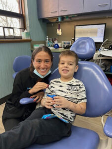 Friendly female hygienist leaning next to a young boy in a dental chair
